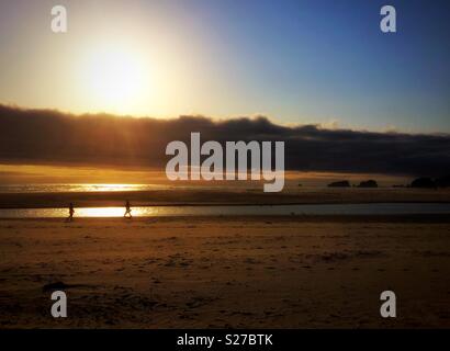 Camminare sulla spiaggia al tramonto, Cannon Beach, Oregon, Stati Uniti d'America. Foto Stock