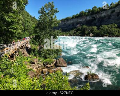 I turisti a piedi lungo l'acqua bianca rapide del fiume Niagara in Niagara Falls, Ontario, Canada Foto Stock