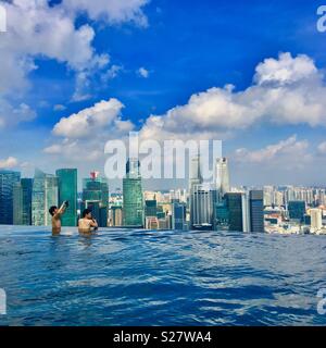 Il Marina Bay Sands Hotel piscina in Singapore con due uomini per scattare delle foto e grattacieli in background Foto Stock