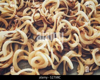 Primo piano immagine di materie spiralizzato patate bianche rivestite in olio di oliva sale e pepe Foto Stock