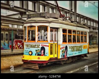 Una fermata del tram che corre sul percorso 18 nel centro di Lisbona, Portogallo. Elettrico di questo sistema di trasporto pubblico è stata introdotta nel 1901. La maggior parte delle vetture del tram sono decorate con inserzioni. Credito foto - © COLIN HOSKINS. Foto Stock