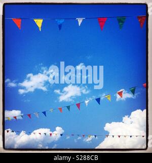 Colorato pennant bunting contro il cielo blu con nuvole, celebrazione, divertente, evento Foto Stock