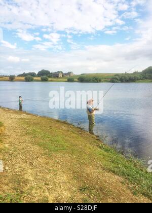 Ragazzo e suo nonno la pesca di trote per Scout Dike serbatoio, Pennistone, South Yorkshire, Inghilterra. Foto Stock