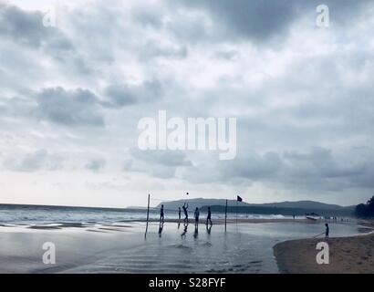 Ragazzi giocare pallavolo sulla spiaggia al tramonto sulla spiaggia di Agonda in Goa, India Foto Stock