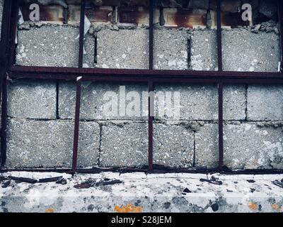 Metallo finestra incorniciata murate con blocchi di cemento e mattoni di argilla Foto Stock