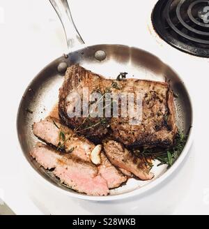 Pan fritto bistecca di fianco con aglio e rosmarino. Foto Stock