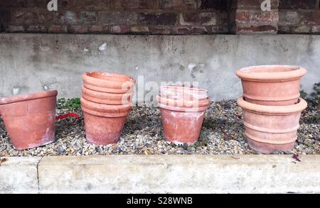 Argilla e terracotta vasi per piante impilati in righe all'interno di una serra in uno sfondo di giardinaggio Foto Stock