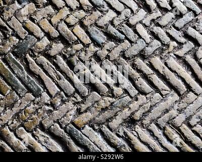 Motivo a spina di pesce di un pavimento in pietra formata da ciottoli di forma rettangolare o cubetti Foto Stock