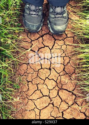 Scarpe da trekking da sopra sul secco suolo incrinato Foto Stock