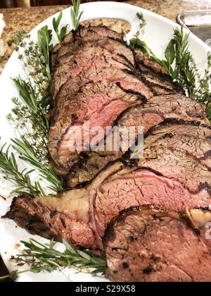 Belle fette di costolette di carne su un piatto bianco guarnito con rosmarino. Foto Stock