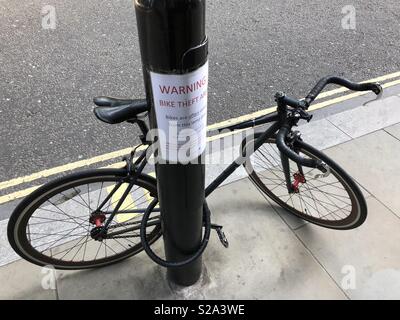 Incatenati bicicletta accanto alla segnalazione furto bici segno Londra Foto Stock