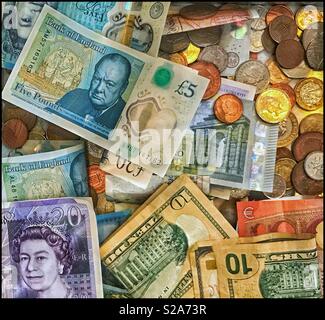 Una raccolta di varie banconote e monete. Chiaramente visibili sono le venti sterline nota, il nuovo 5 Pound Sterling nota e i dieci Stati Uniti Dollar nota/Bill. Una foto per l'economia globale. Foto Stock