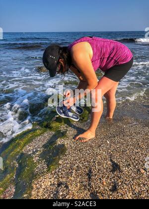 Donna cerca conchiglie sulla spiaggia nel sud della Spagna. Foto Stock