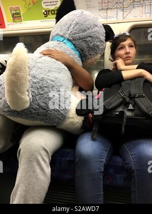 Grande Giocattolo del cane sul sat mans lap sulla metropolitana Jubilee line a Waterloo accanto alla donna sacco di contenimento Foto Stock