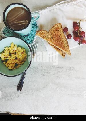 Una sana prima colazione su un tavolo con copia spazio. Uova strapazzate, frumento toast, uva e caffè. Foto Stock