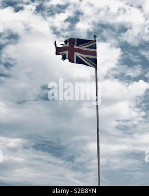 Un vecchio mezza distrutta Union Jack flag sbattimenti nel vento Foto Stock