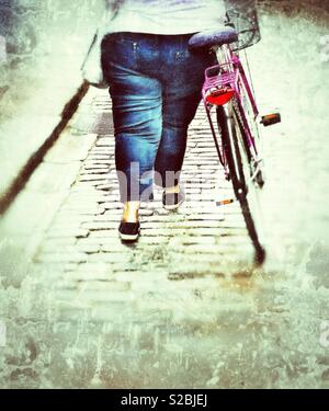 Il sovrappeso donna obesa spingendo bike collina di ciottoli, Stoccolma, Svezia Foto Stock