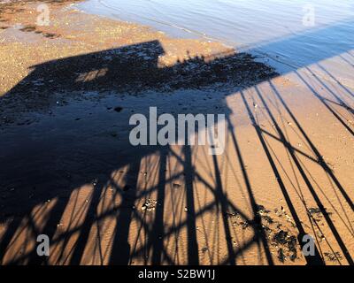 Ombre di Penarth molo sulla spiaggia di Boiano, nel tardo pomeriggio, Ottobre. Foto Stock