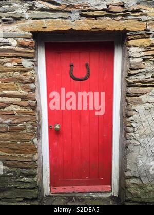 Buona fortuna - Porta Rossa nel muro di pietra casa con ferro di cavallo fortunato, Stromness, Orkney Foto Stock