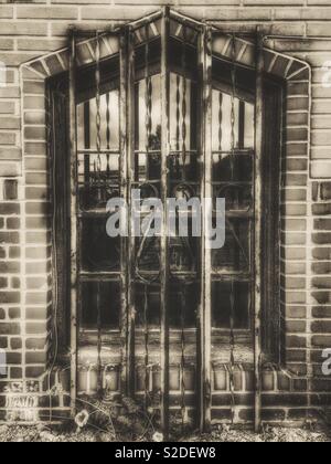 Ferro finestra grattugiato su un vecchio edificio in mattoni Foto Stock
