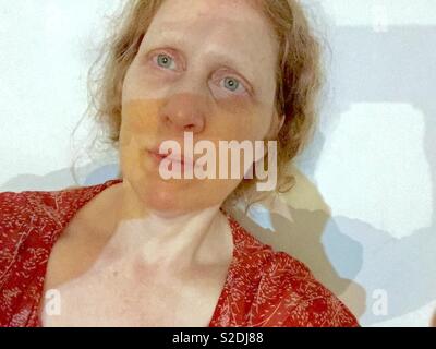 Donna dai capelli rossi con frane e occhi azzurri che prendono un selfie su uno sfondo bianco. Foto Stock