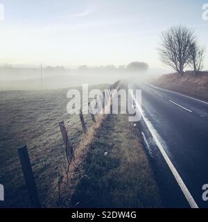 Paese di strada nella nebbia in una mattina inverni Foto Stock