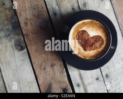 Tazza di cappuccino caldo con caffè e a forma di cuore ad latte art panna  montata in tono vintage, copia dello spazio sul tavolo di legno, amore o il  concetto di relax