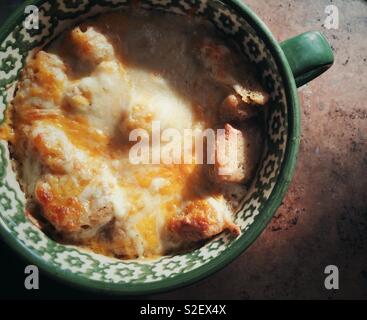 Vista ingrandita di fatti in casa zuppa di cipolle Francese ricoperto di formaggio arrostito e crostini in una grande tazza di zuppa Foto Stock