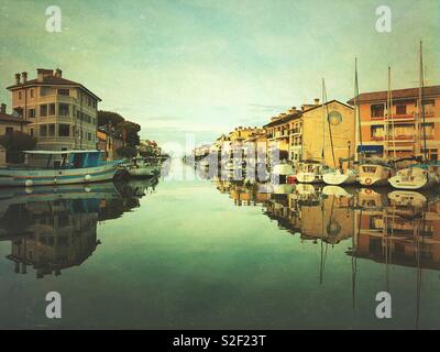 Gli edifici e le barche che riflette in grado Canal - Grado Friuli Venezia Giulia, Italia Foto Stock