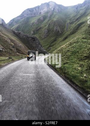 Guardando verso il basso una strada di montagna come un Land Rover rigidi in discesa attraverso terreni accidentati Foto Stock