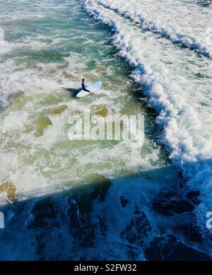 Un surfista maschio esce fuori verso il surf. Manhattan Beach, California USA Foto Stock