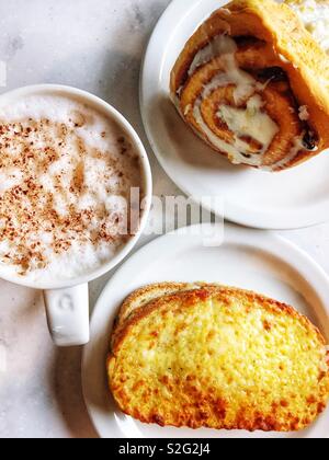 Cappuccino, sandwich tostato e cannella rotolo ad un cafe'. Foto Stock