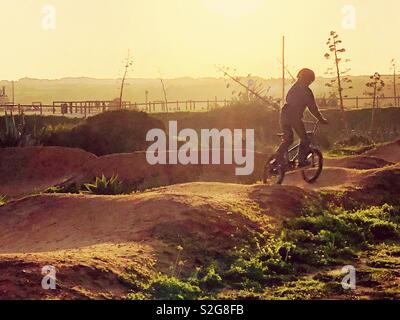 In sella ad una bici bmx al tramonto Foto Stock