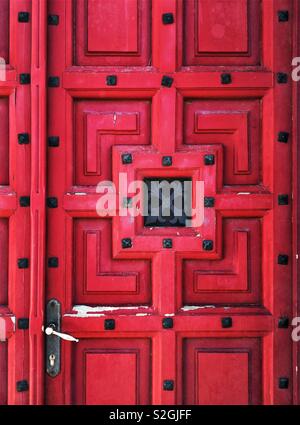 Rosso porta in legno con prigionieri ornamentali Foto Stock