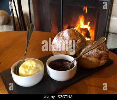 Buon cibo momenti: una crema tè serviti su una domenica pomeriggio davanti ad un accogliente pub ruggente fuoco. Foto Stock