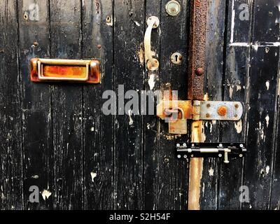 Vecchia porta bloccata con peeling nero vernice e un letterbox. Foto Stock