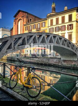 Le biciclette parcheggiate dal bordo del Naviglio Grande nei pressi di un ponte in Milano, Italia Foto Stock