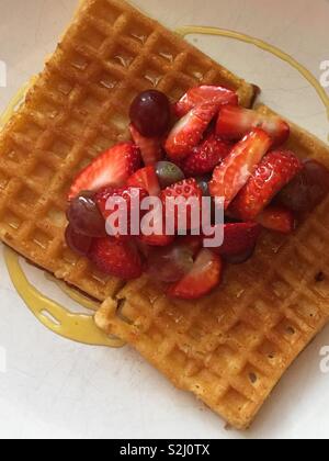 Fresca frutta vibranti che comprende le fragole su hot waffles belgi. Colazione perfetta, dessert o cibo di strada trattare Foto Stock