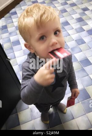 Due anni di vecchio ragazzo giocando con una carta di credito nella sua bocca. Foto Stock