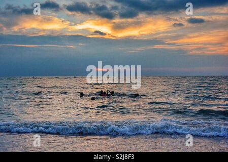 Nuoto in mare al tramonto. Foto Stock