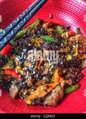 Fritti di riso rosso con manzo e verdure, wok cibo cinese close up Foto Stock