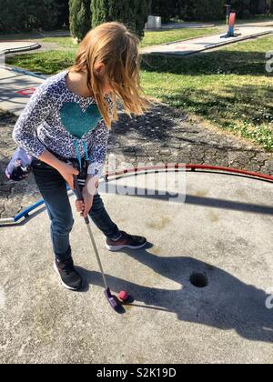 Ragazza che gioca mini golf Foto Stock