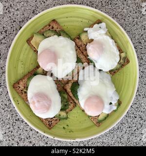 Le uova in camicia su tutto il pane di grano con avocado per una sana prima colazione Foto Stock