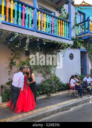 Celebrando e posa per la fotocamera nella parte anteriore di un variopinto edificio coloniale nel Getsemani quartiere di Cartagena, Colombia. Foto Stock