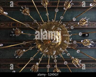 Molto elegante e di elaborare un lampadario appeso dal verde ornato soffitto a travi. Foto Stock