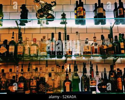 Bottiglie di bevande spiritose sui ripiani in un cocktail bar Foto Stock
