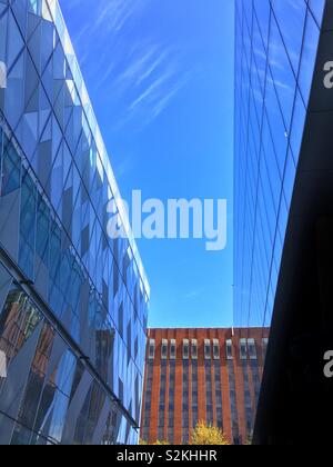 Gli edifici che riflette il cielo blu e nuvole in Spiningfields area di Manchester Foto Stock