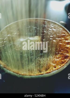 Spolverata di zucchero nel latte schiumoso tazza di cappuccino. Un moody, movimento sfocati closeup sfondo per gli amanti del caffè. Foto Stock