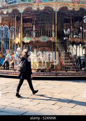 Giovane donna parigina con zaino passeggiate passato giostra Vicino a Hotel de Ville Foto Stock