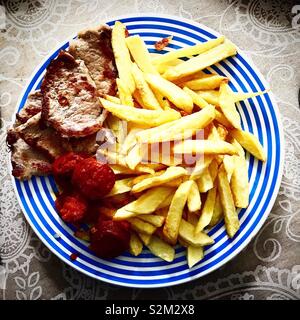 Patate fritte, salsicce ( ) il chorizo iberico e bistecche di carne in Prado del Rey, Sierra de Cadice, Andalusia, Spagna Foto Stock